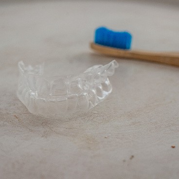 Aligner sitting next to toothbrush on cabinet