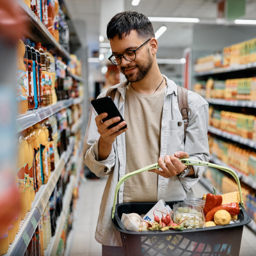 Man smiling while looking at grocery list on phone