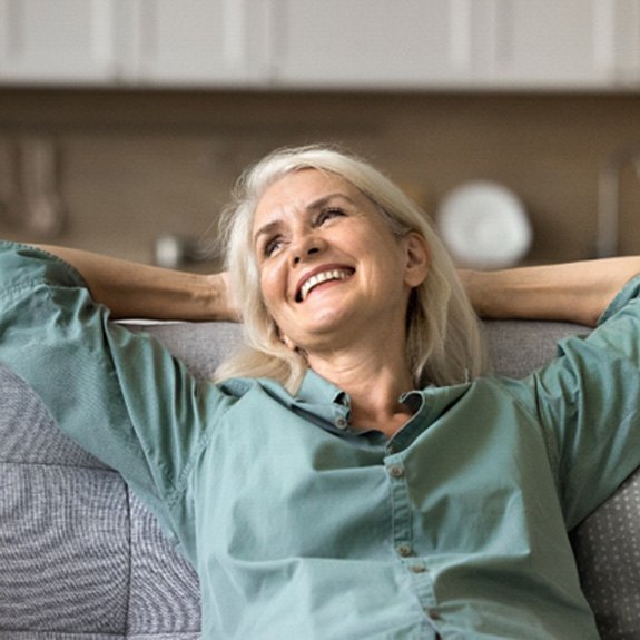 Senior woman sitting back on couch and smiling
