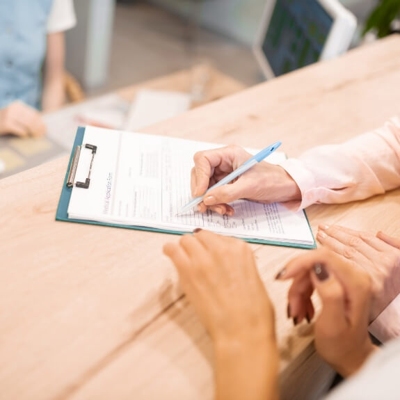 Close up of patient filling out form on a clipboard