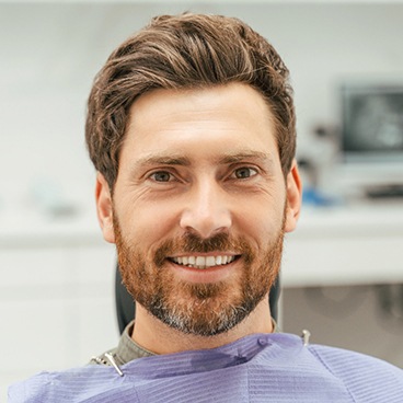 Bearded man sitting in dental chair smiling