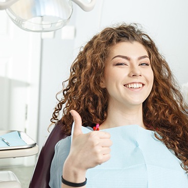 Female patient with curly hair giving thumbs up