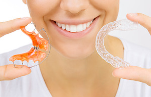 Woman holding retainer and Invisalign aligner