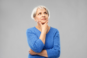 Older woman in blue shirt looking thoughtful